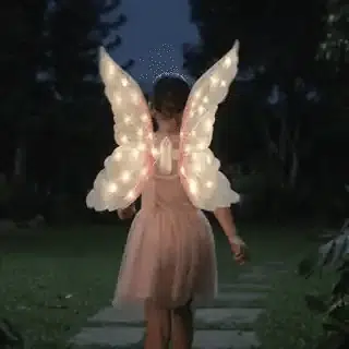 Niña caminando de noche con las Alas Mágicas de Ángel™ iluminadas