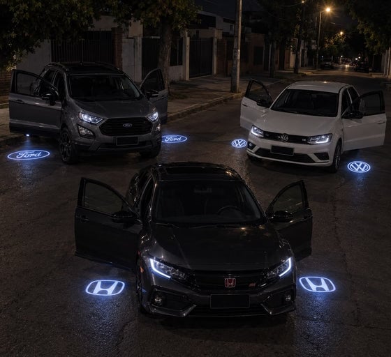 Tres autos de noche, cada uno proyectando su logo iluminado en el asfalto junto a la puerta abierta